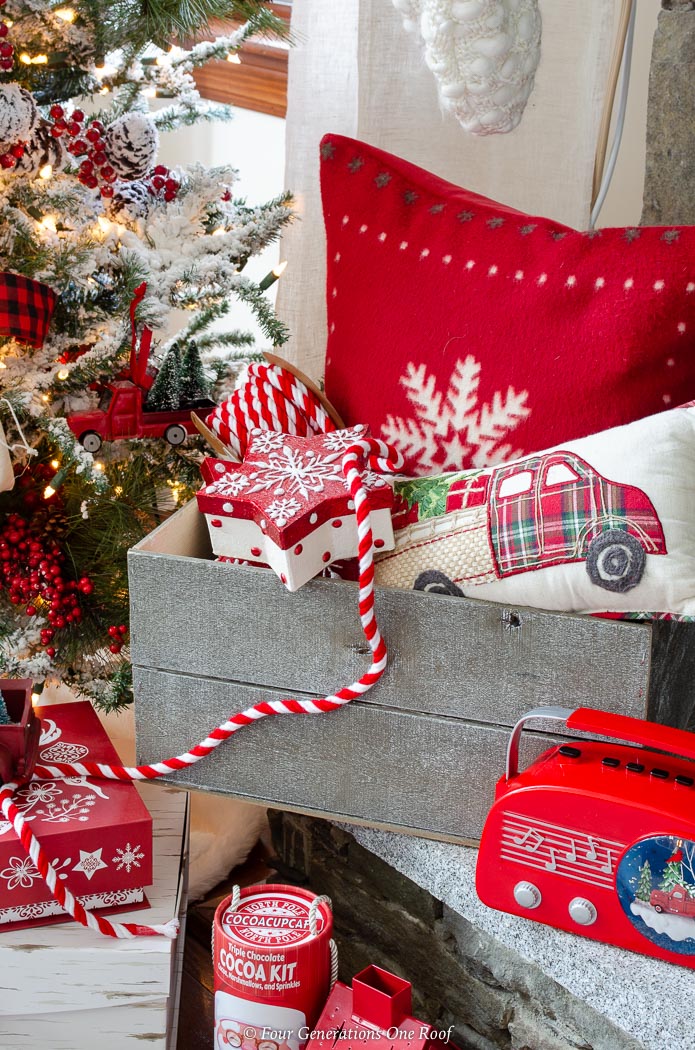 DIY gray wooden Christmas crate filled with red snowflake pillow, presents, red striped ribbon, red vintage boom box